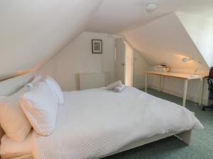 a bedroom with a white bed and a desk at Footdee Cottage in Aberdeen