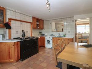 a kitchen with wooden cabinets and a table in it at Footdee Cottage in Aberdeen