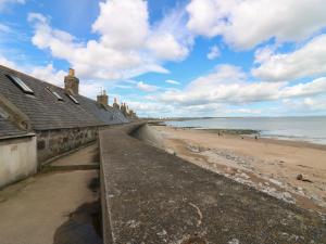 a view of a beach with a building and the ocean at Footdee Cottage in Aberdeen