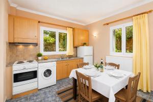 a kitchen with a table with chairs and a white appliance at Villa Penelope Sea View in Argostoli