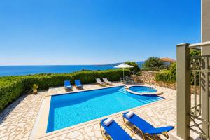 a swimming pool with chairs and the ocean in the background at Villa Penelope Sea View in Argostoli