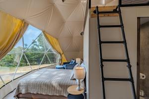 a bedroom in a tent with a bed and a ladder at Pilot Mountain Glamping Resort in Pinnacle