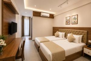a hotel room with two beds and a desk at Seaking Suites-MG Road in Cochin