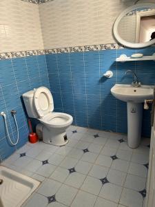 a blue tiled bathroom with a toilet and a sink at Résidence El hechene in Ḩawmat al Ḩashshān