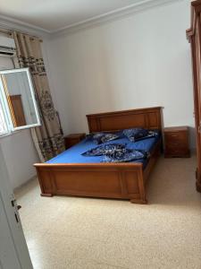 a bedroom with a bed with blue sheets and a mirror at Résidence El hechene in Ḩawmat al Ḩashshān