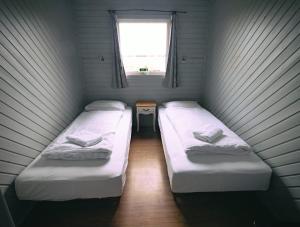 two beds in a small room with a window at Ásgarður Guesthouse in Hvolsvöllur +17 photos
