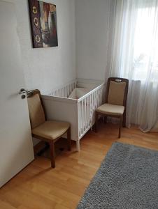 a baby crib with two chairs in a room at Ferienwohnung Lottstetten in Lottstetten +25 photos