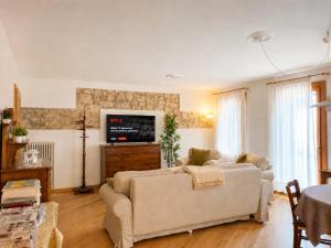 a living room with a couch and a tv at Lhousing - Ideale per Famiglie e Gruppi in Asiago