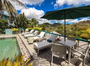 a patio with chairs and an umbrella next to a pool at Titi Vacation Homes in Cobbs Cross