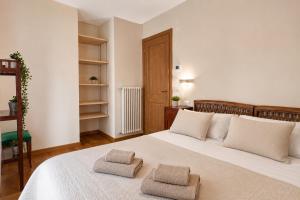 a bedroom with a large white bed with two towels on it at Lhousing - Ideale per Famiglie e Gruppi in Asiago