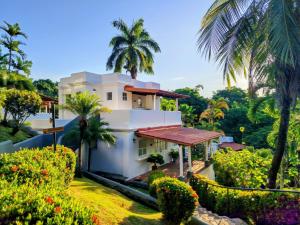 an exterior view of a house with palm trees at Alma Vida Hotel in Manuel Antonio