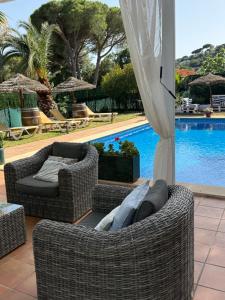 a patio with two wicker chairs next to a pool at Le petit studio in Calonge