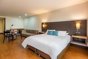 ein Hotelzimmer mit einem großen Bett und einem Schreibtisch in der Unterkunft Hotel Morrison Usaquén in Bogotá