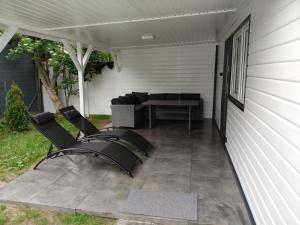 a patio with two chairs and a couch on a porch at Radosna Zatoka - DOMKI Z OGRODZENIEM in Międzywodzie