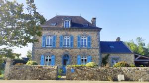 an old stone house with blue windows and a fence at Ty Maen - Étage avec chambre, coin salon, toilettes et salle de bain in Erdeven