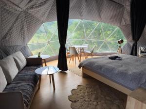 a room with a bed and a couch in a tent at Ursa Camp Mountain Glamping in Gornje Lipovo