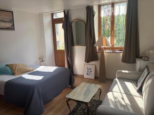 a bedroom with a bed and a couch and a chair at Au fil de Lods in Lods
