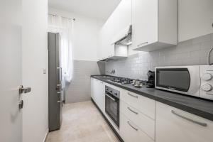 a white kitchen with a microwave and a stove at Casa Amelia - Elegant Suite [parcheggio gratuito] in Parma