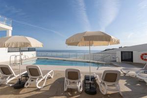 a patio with chairs and umbrellas and a swimming pool at NerjaPlus Terraza de Ladera Apartamento V11 in Nerja