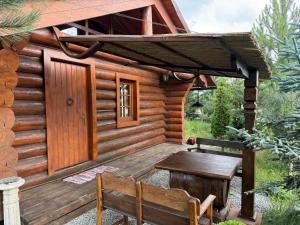 a wooden cabin with a table and a bench at Cabana Vadim in Turda