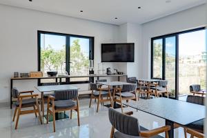 a dining room with tables and chairs and windows at Vila 2M in Sarandë
