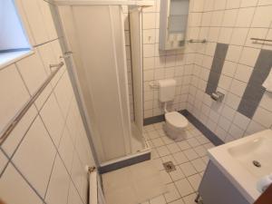 a white bathroom with a toilet and a sink at Csendes Panoráma Apartman in Balatonalmádi