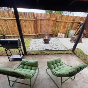 two green chairs and a grill in a backyard at Raven in Stormsrivier
