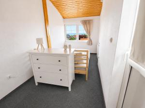 a bedroom with a white dresser and a window at Csendes Panoráma Apartman in Balatonalmádi
