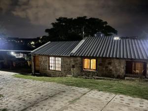 a stone house with a tin roof at night at Cabañas Wasirumi Pileta y bajada al Rio in Bialet Massé