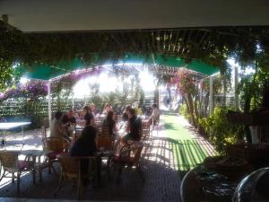 a group of people sitting at a restaurant under a pergola at Hotel Vela Velo Club Vieste in Vieste