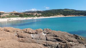 a beach with people in the water and rocks at Casa Alby in Nulvi
