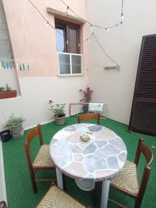 a patio with a table and chairs on a green floor at Casa Alby in Nulvi