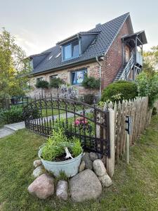 a fence in front of a house with a plant at Altes Siedlerhaus Nesebanz in Gustow