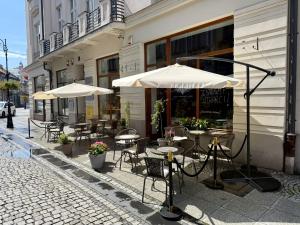 an outdoor cafe with tables and chairs and umbrellas at Przy Deptaku VAT Parking z pilotem do bramy in Nowy Sącz