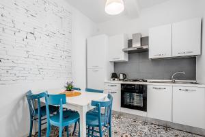 a kitchen with a white table and blue chairs at Le Finestre Sul Borgo 1 in Parma