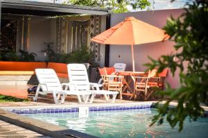 a table and chairs and an umbrella next to a pool at Casa Quinta MYK in Ciudad del Este