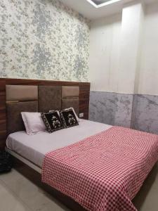 a bedroom with a bed with a red checkered blanket at Hotel Lucifer by Evening Star in Bathinda
