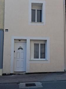 a white building with a door and two windows at Maison SYD saint-Junien in Saint-Junien