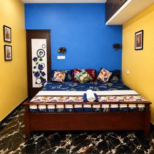 a bed in a room with a blue wall at La Baie Homestay in Pondicherry