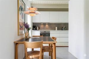 a kitchen with white cabinets and a wooden table and chairs at Gladeholm in Kivik