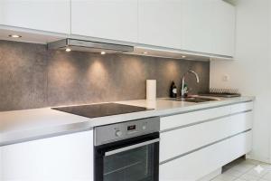 a kitchen with white cabinets and a stove top oven at Gladeholm in Kivik +16 photos