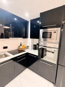 a kitchen with black cabinets and a stainless steel appliance at Punta Prima Sun & Sea Apartament in Punta Prima