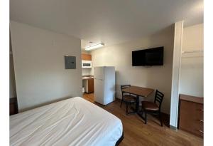 a room with a bed and a table and a refrigerator at Studio 6 Rancho Cordova, CA in Rancho Cordova