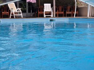 a swimming pool with chairs and blue water at Gîte - Le Moulin Bernard - Béganne in Béganne