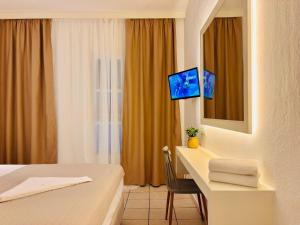 a hotel room with a bed and a desk with a tv at Vaya Zorba Studios in Skiathos