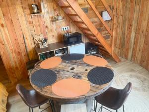 a wooden table and chairs in a room with a kitchen at La Cabane Tonneau - Les Pieds dans le Pré in Les Landes-Génusson