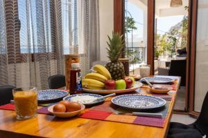 a wooden table with plates of food and fruit on it at Auster House Santorini in Kamari