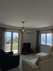 a living room with a couch and large windows at Azzurre Premium Aparthotel in Sarandë