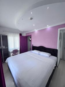 a bedroom with a large bed with a purple wall at Dardanos Pension in Hamidiye +44 photos