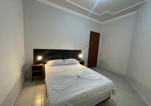 a white bedroom with a bed and a desk at 474 Flats e Suítes Standard in Ipatinga